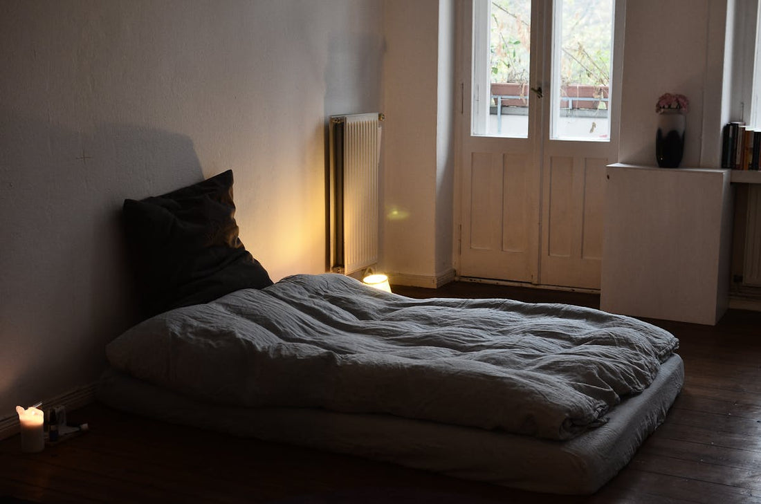 Cozy bedroom with warm lighting, soft blankets, and candles for cozymaxxing - Mattress Miracle Brantford
