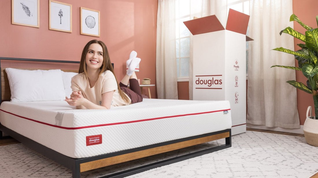 Douglas mattress set up on a platform bed beside its bed-in-a-box shipping box - Mattress Miracle Brantford