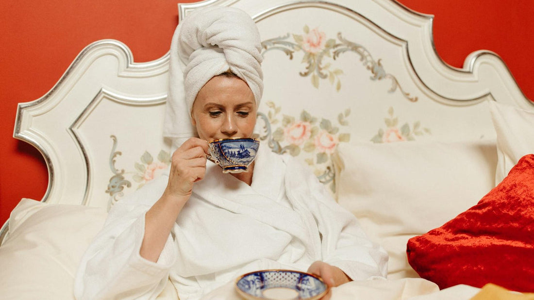 Woman resting comfortably in bed with a cup of herbal tea - Mattress Miracle Brantford