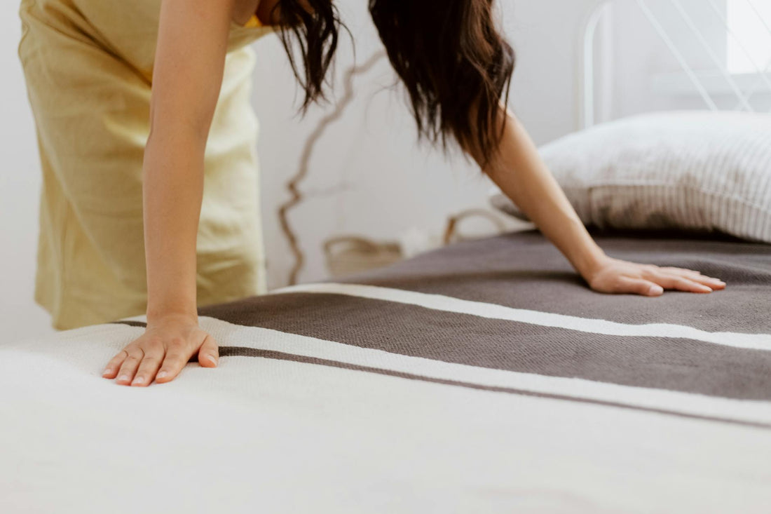 Woman making a clean bed with fresh linens