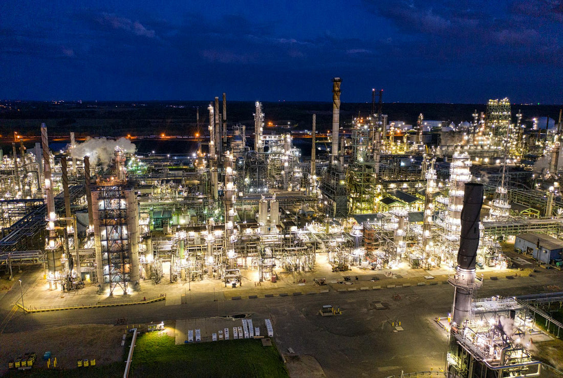 Oil refinery at night with industrial lights in Alberta - Mattress Miracle