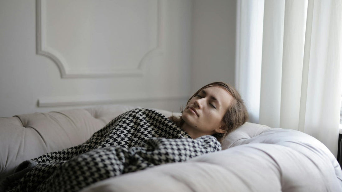 Tired woman resting on a couch during an afternoon slump - Mattress Miracle Brantford